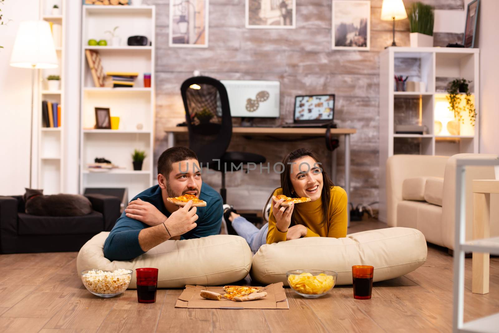 Couple sitting on the floor and watching TV in their living room.