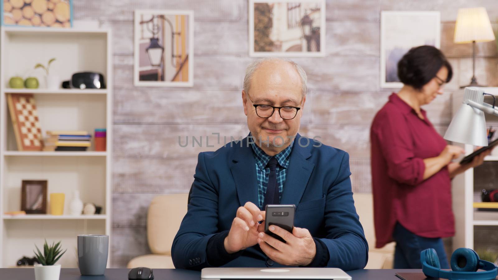 Elderly man with glasses browsing on mobile phone by DCStudio