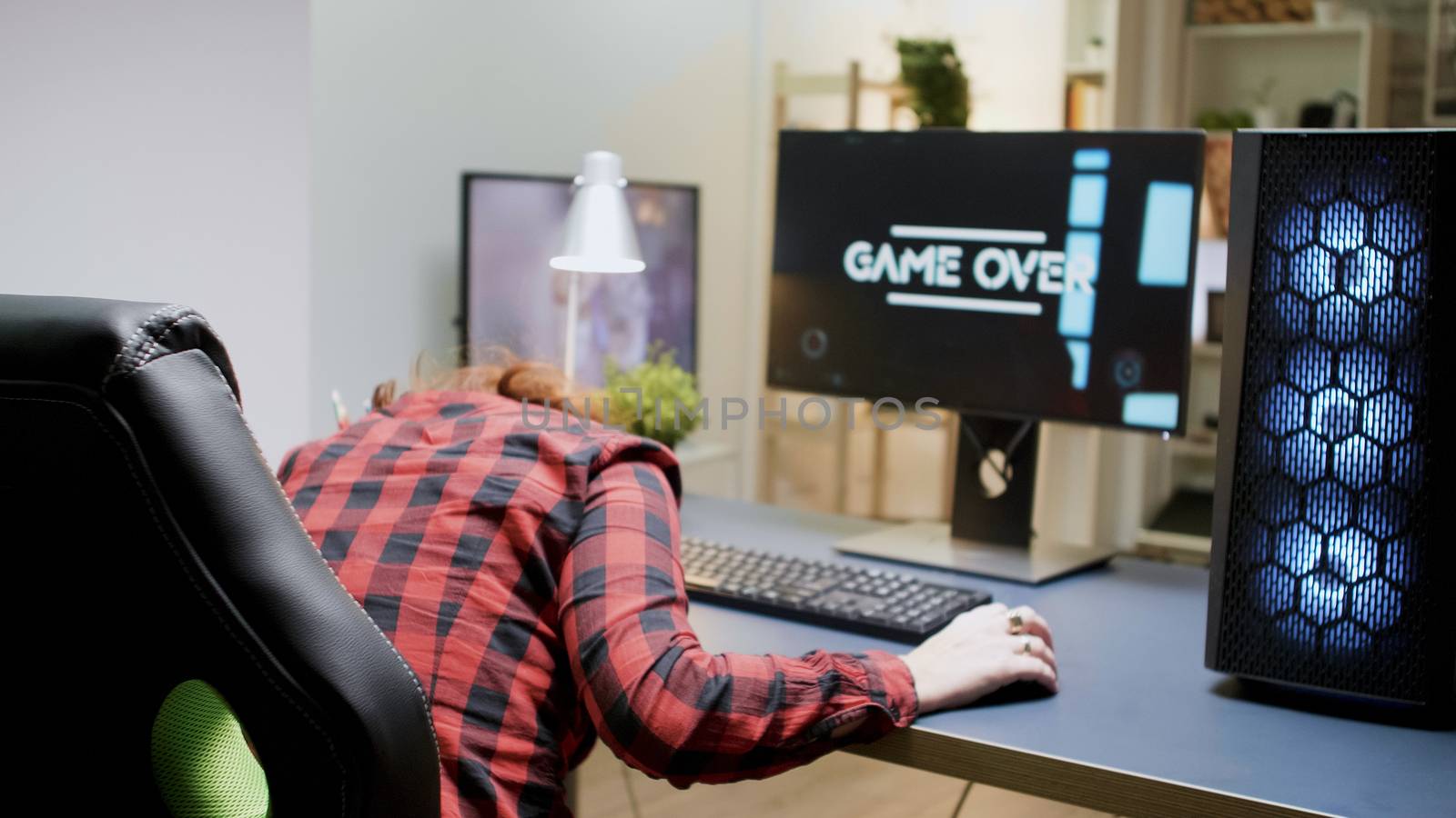 Woman with red hair upset she lost on a shooter online game sitting on gaming chair with headphones on.