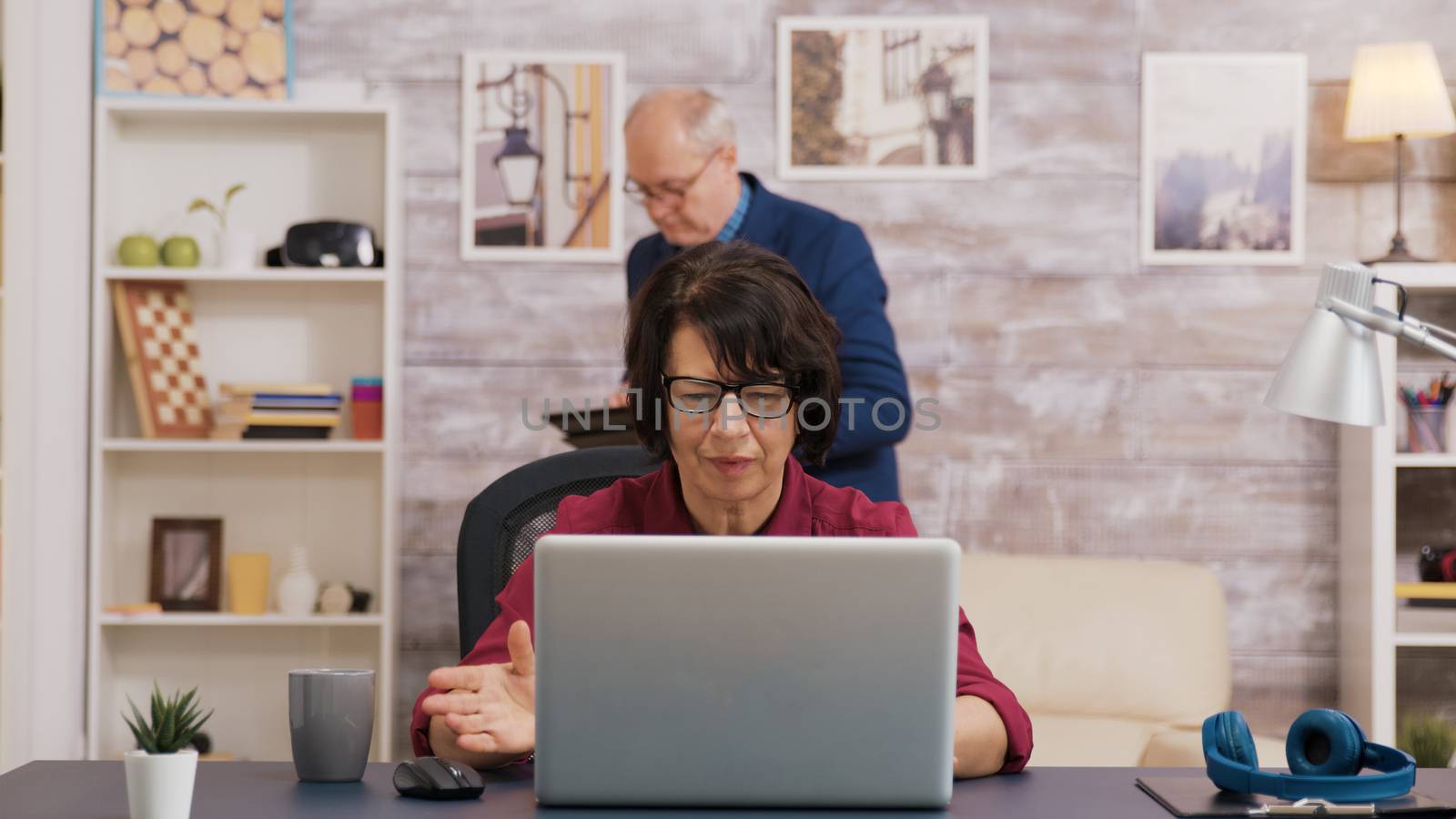 Excited old woman while using laptop in living room by DCStudio