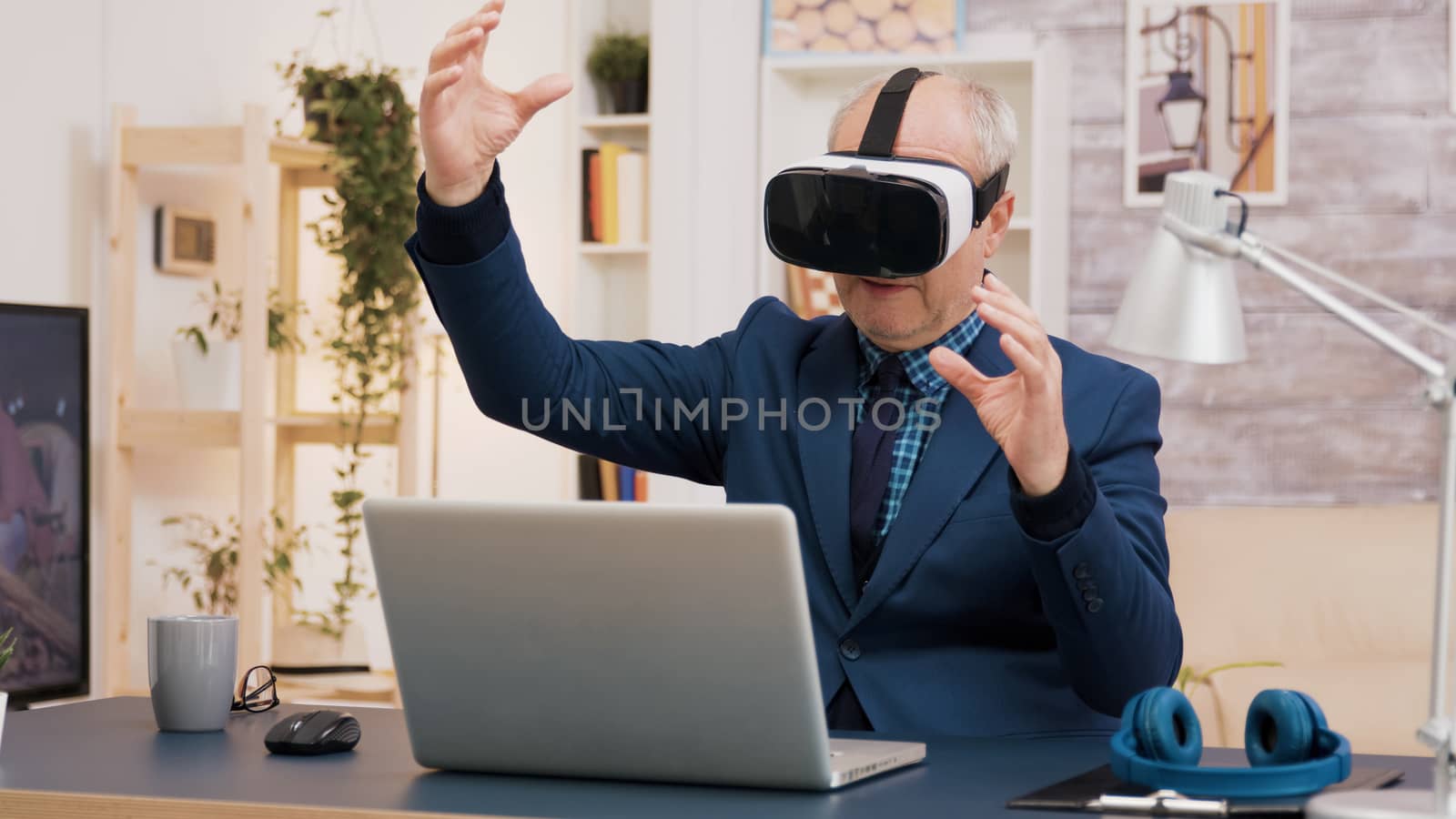 Retired man experiencing virtual reality using vr headset in living room. Cup of coffee on the table.