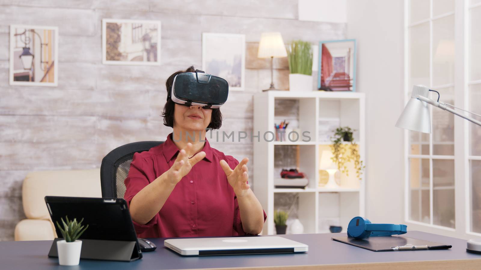 Elderly age woman using virtual reality goggles in living room by DCStudio