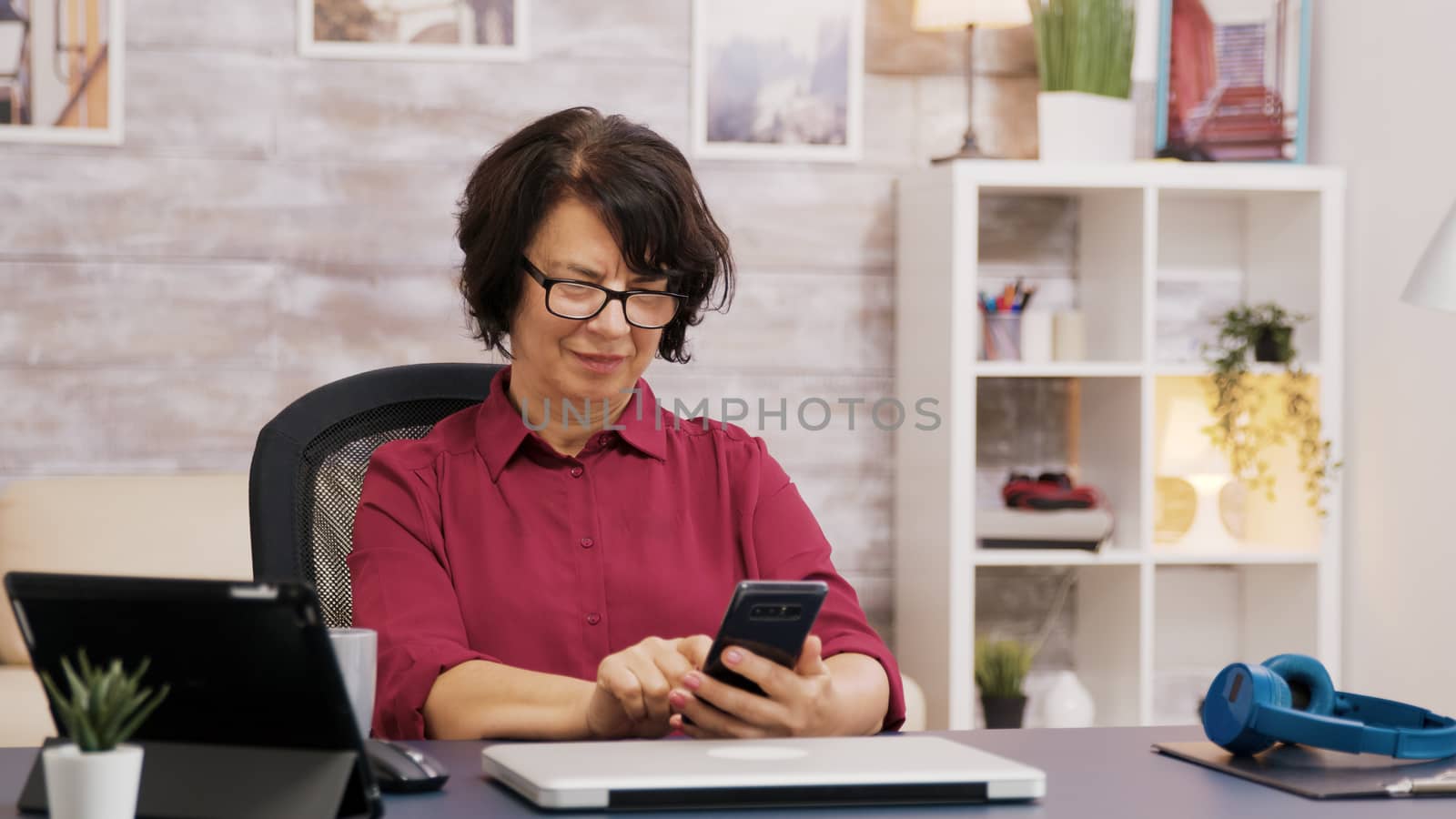 Elderly woman with glasses using tablet and phone by DCStudio