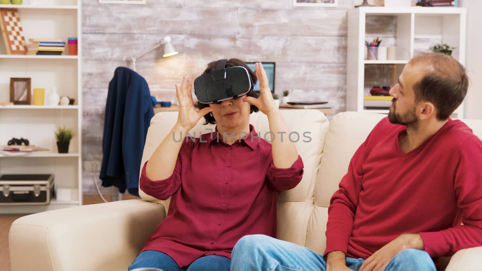 Nephew teaching his grandmother how to use virtual reality headset in living room