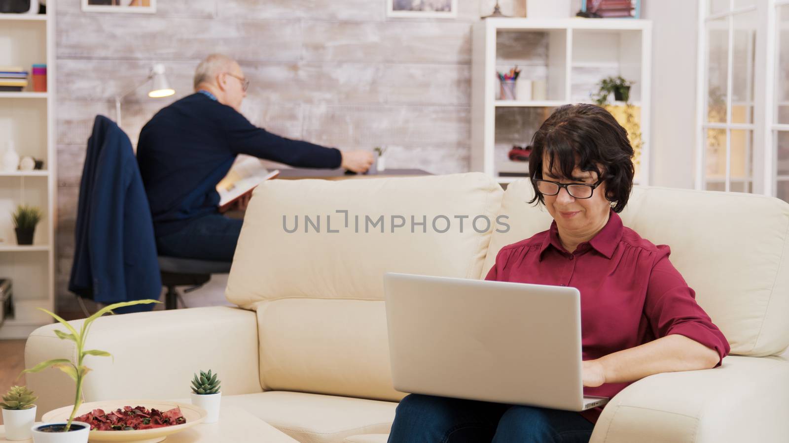Senior woman with glasses working on laptop by DCStudio