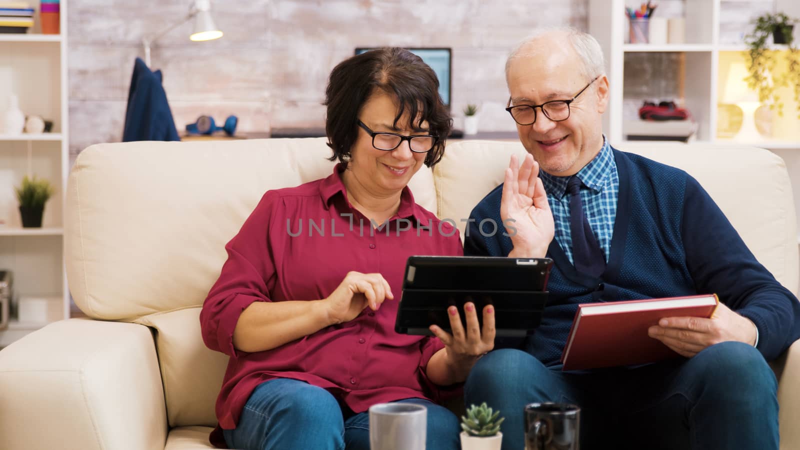 Senior couple waving at tablet during a video call by DCStudio