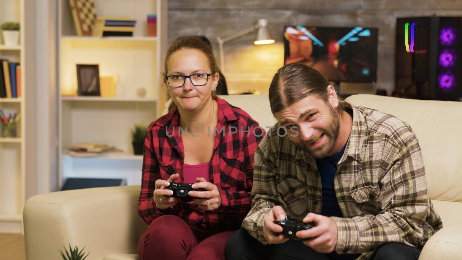 Woman yelling at her boyfriend after losing at video games sitting on couch. Man and woman playing video games.