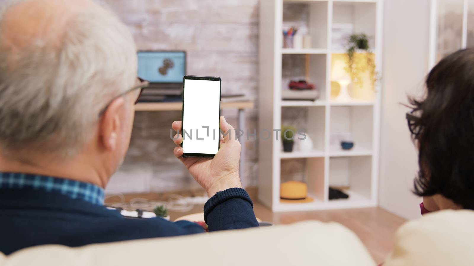 Back view of elderly age couple holding phone with green screen.