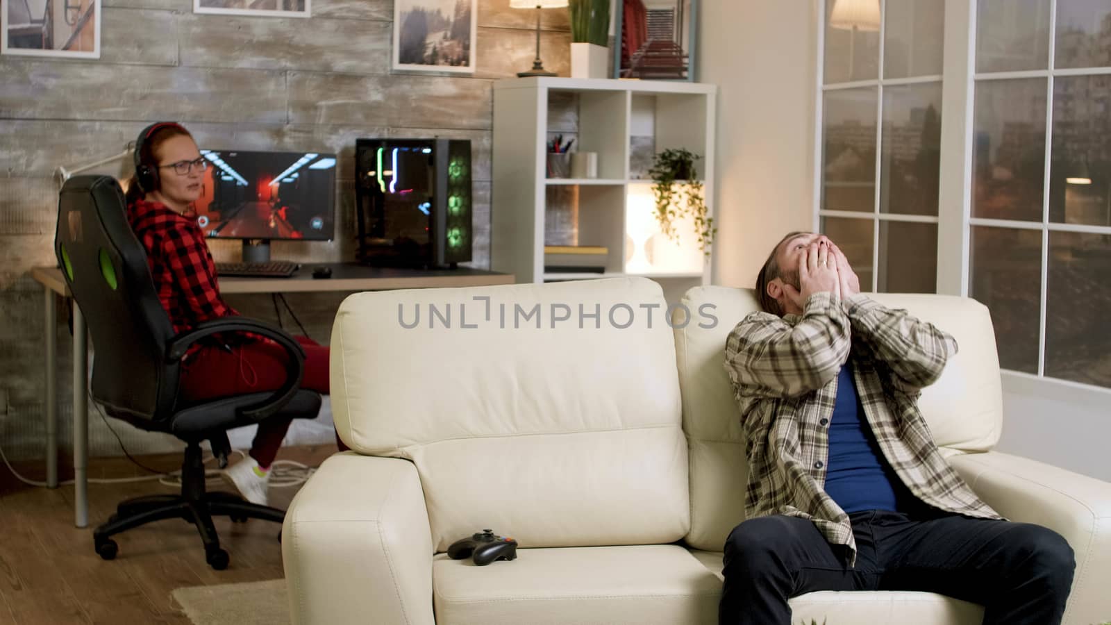 Upset man throwing wireless controller on the couch after losing after playing video games. Girlfriend in the background.