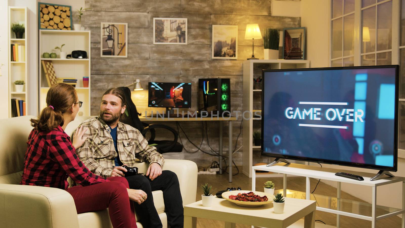 Girlfriend pointing at tv screen while boyfriend is playing video games by DCStudio