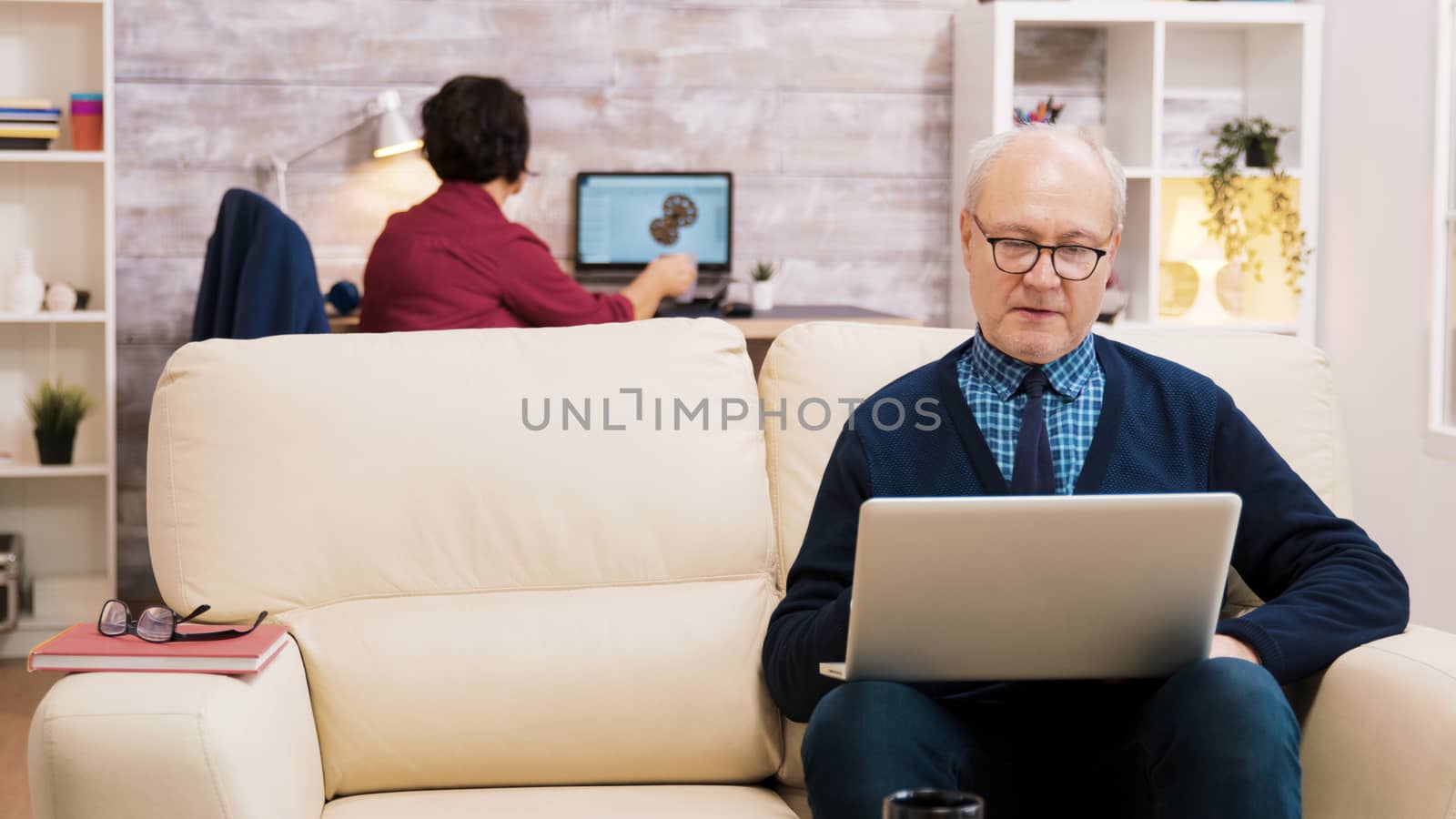 Happy senior middle aged couple sitting on sofa having a video call by DCStudio