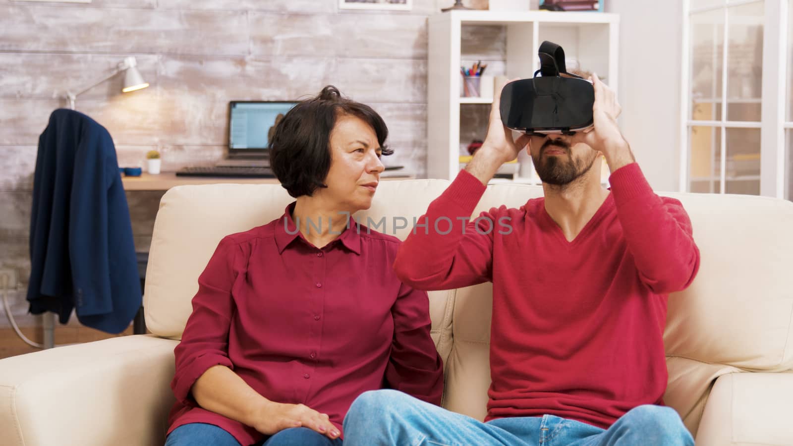 Nephew teaching his grandmother how to use virtual reality headset in living room