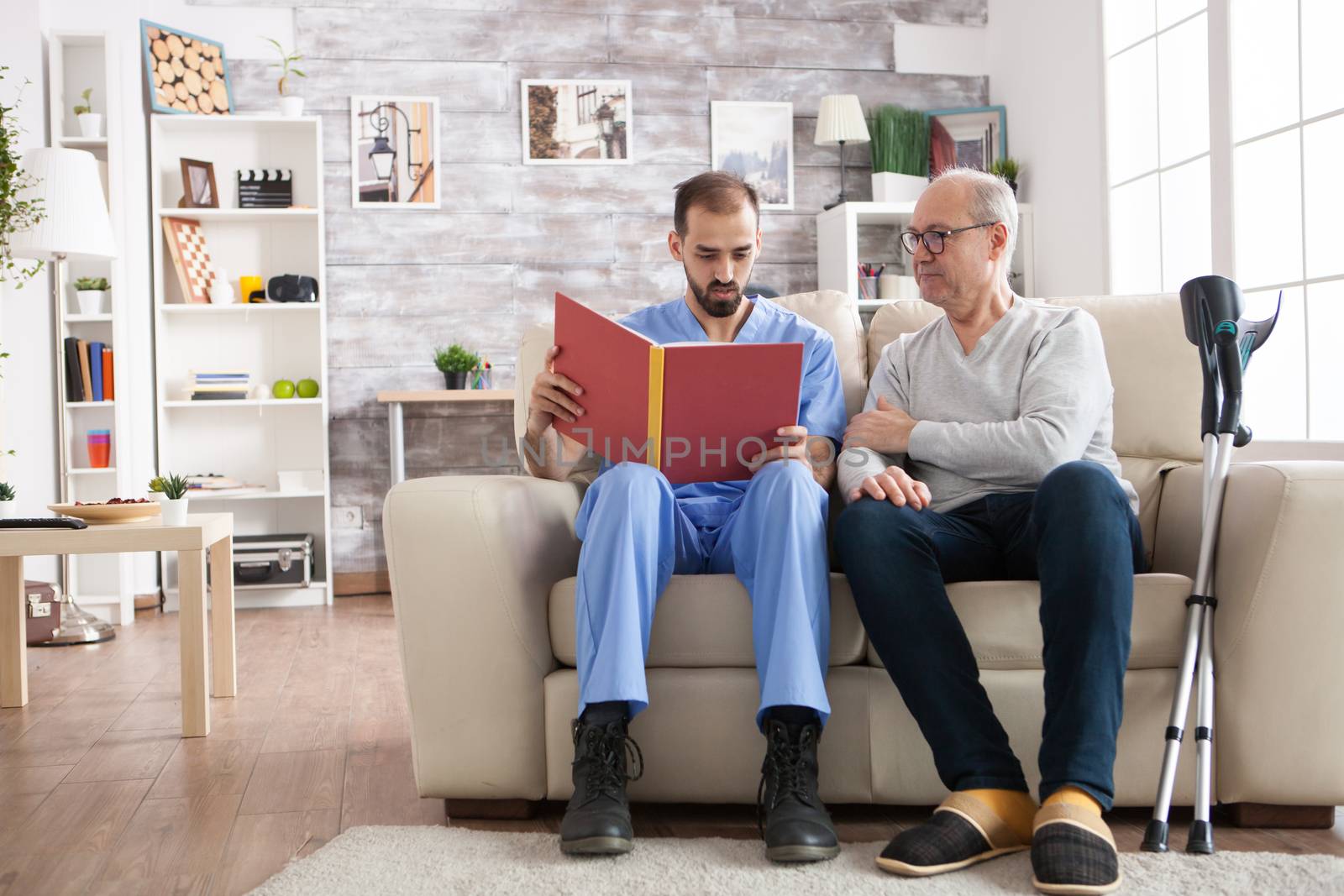 Bearded doctor reading a story in nursing home by DCStudio