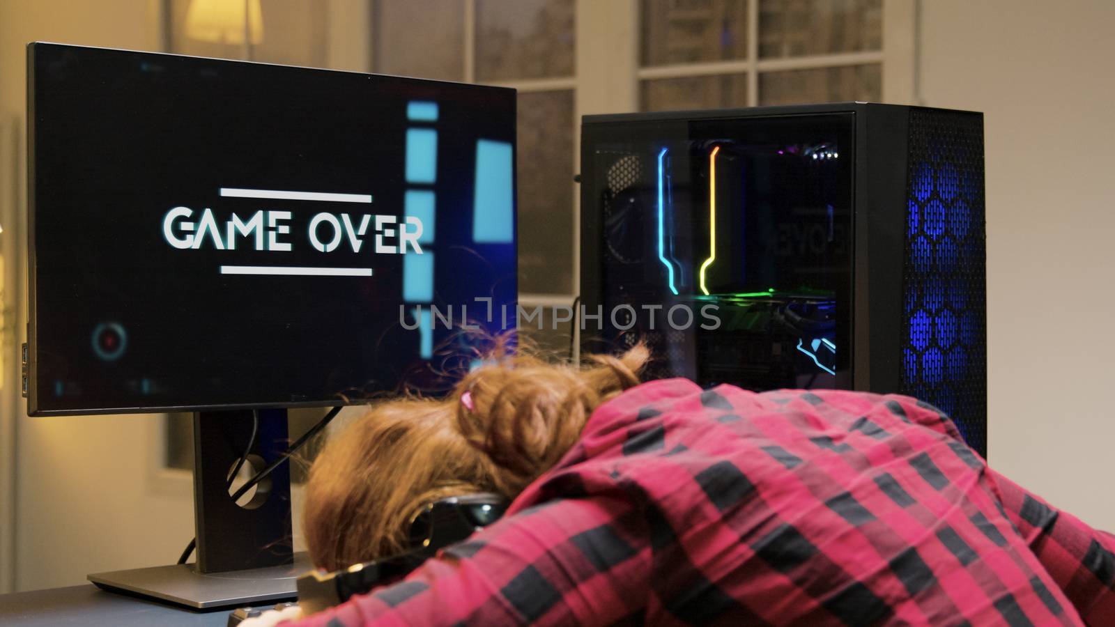 Woman with head on desk after losing a gaming competition. Game over for female gamer.