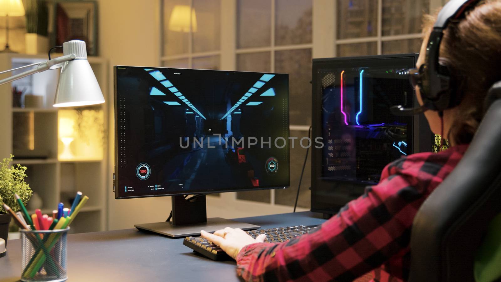 Female gamer with headphones playing shooter games on computer and talking with others players.