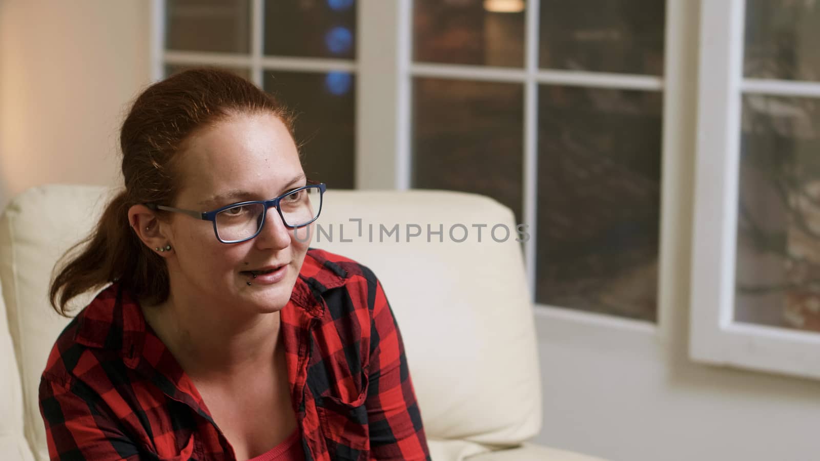 Close up of woman with glasses playing video games sitting on sofa.