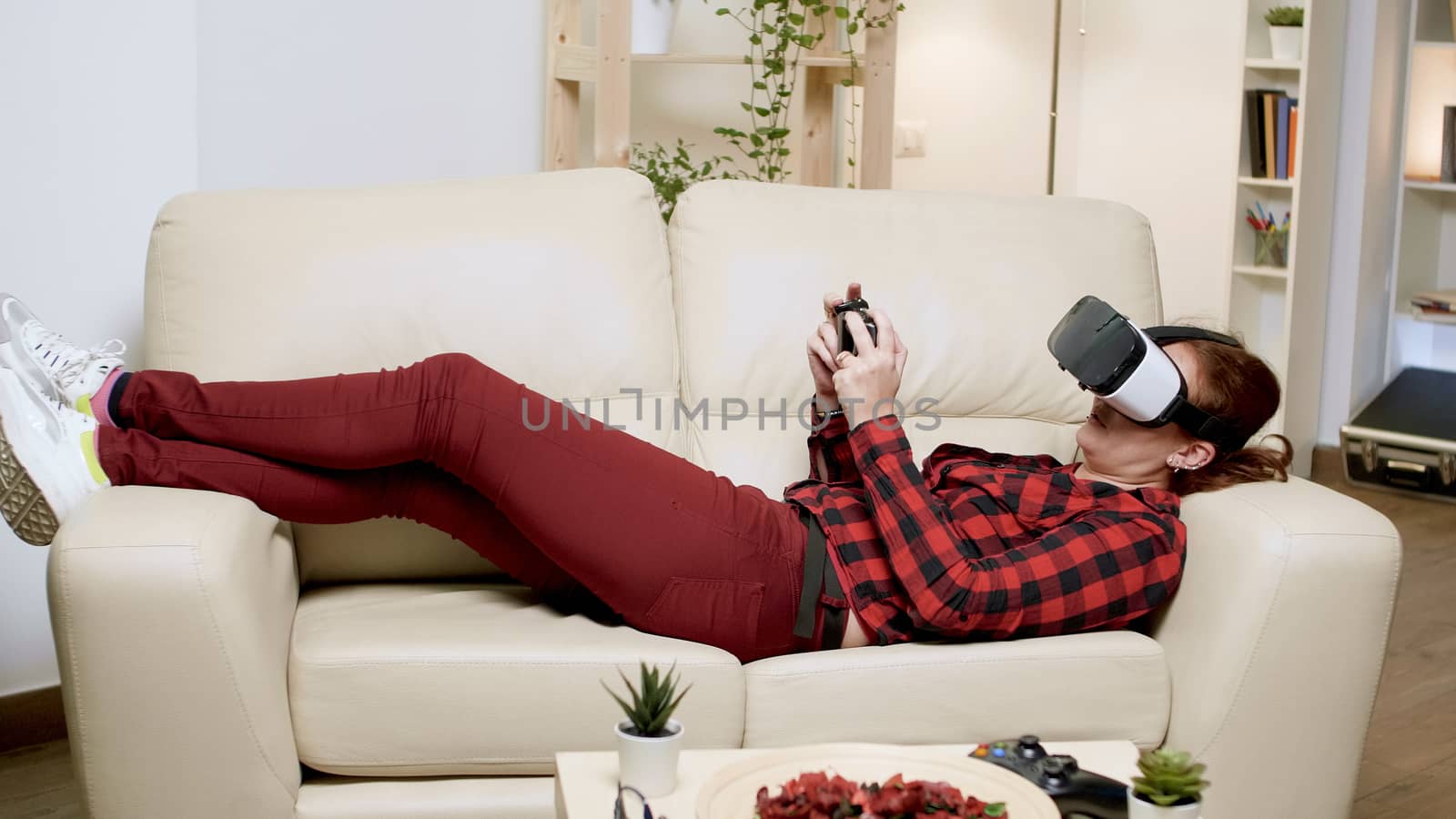 Young woman using modern technology for playing video games. Female using wireless controller.