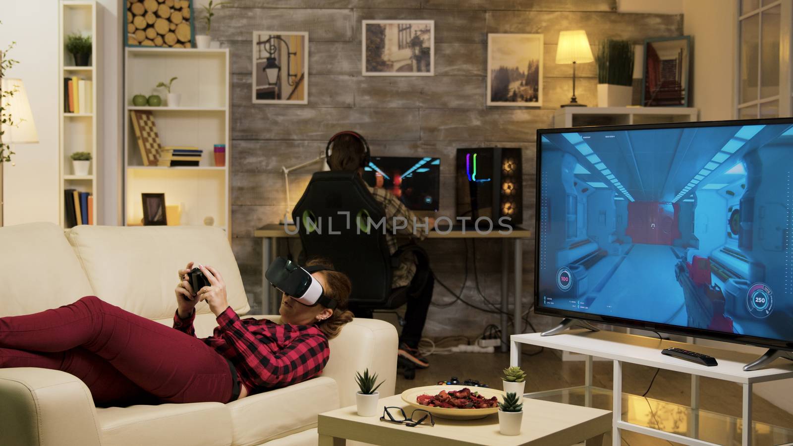 Woman lying on sofa playing video games using vr headset by DCStudio