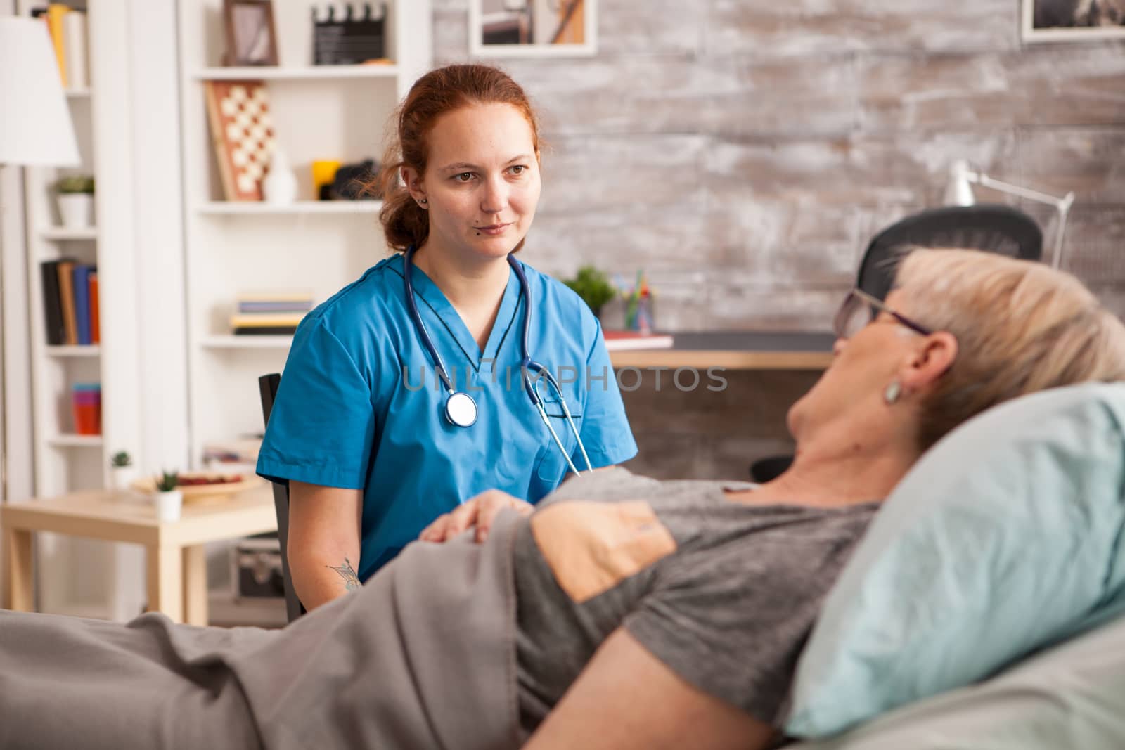 Female nurse with stethoscope listening old woman story in a nursing home.