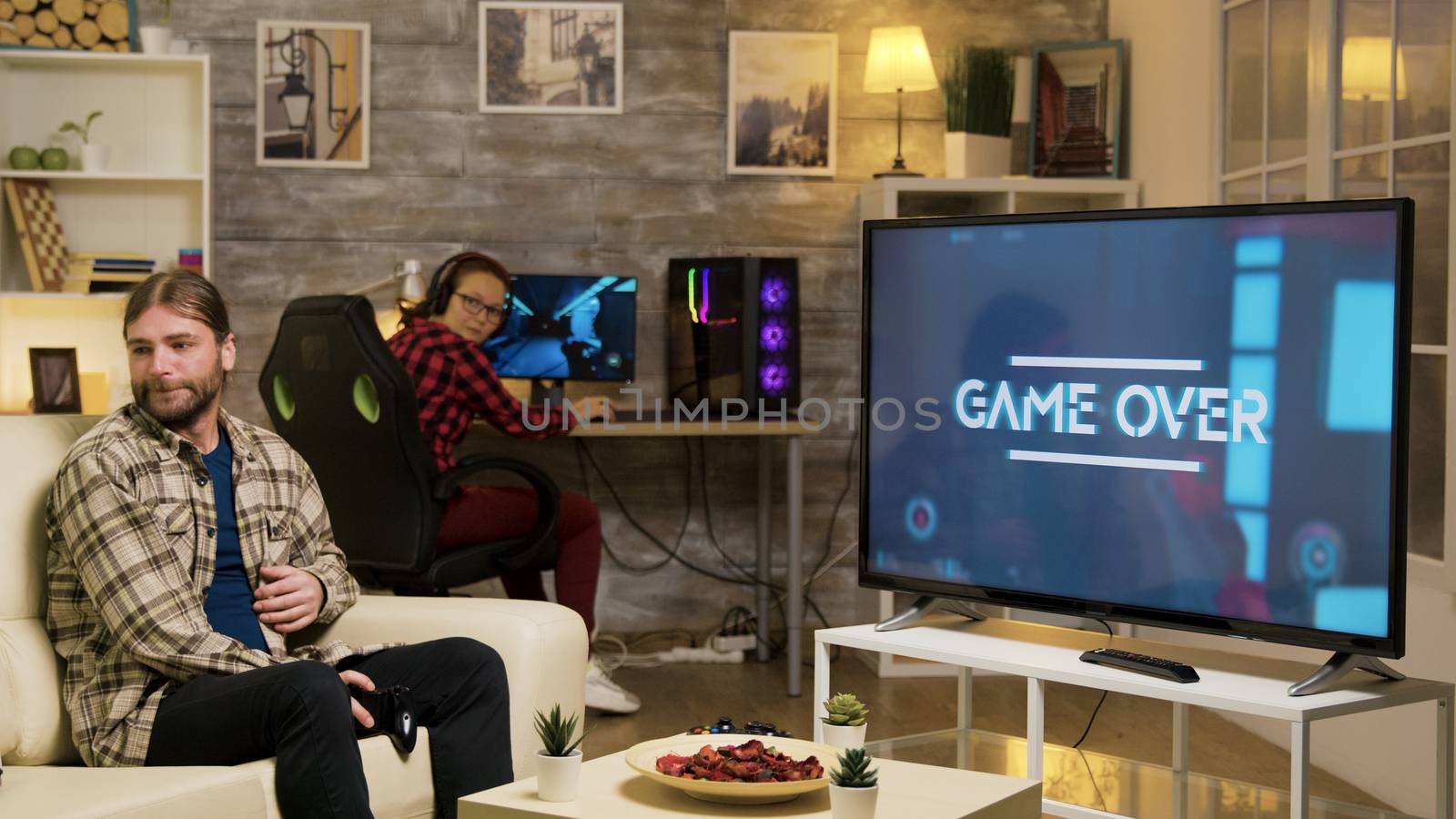 Game over for a young playing video games with vr headset sitting on sofa. Girlfriend looking at boyfriend after losing at video games.