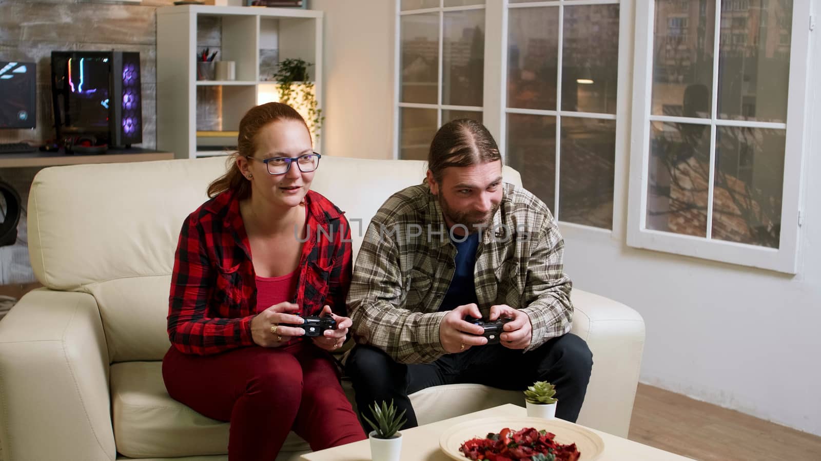 Couple in their 30's relaxing playing video games using wireless controllers. Happy relationship.