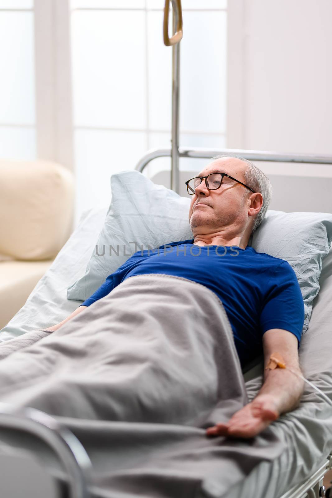Retired old man in nursing home laying on bed by DCStudio