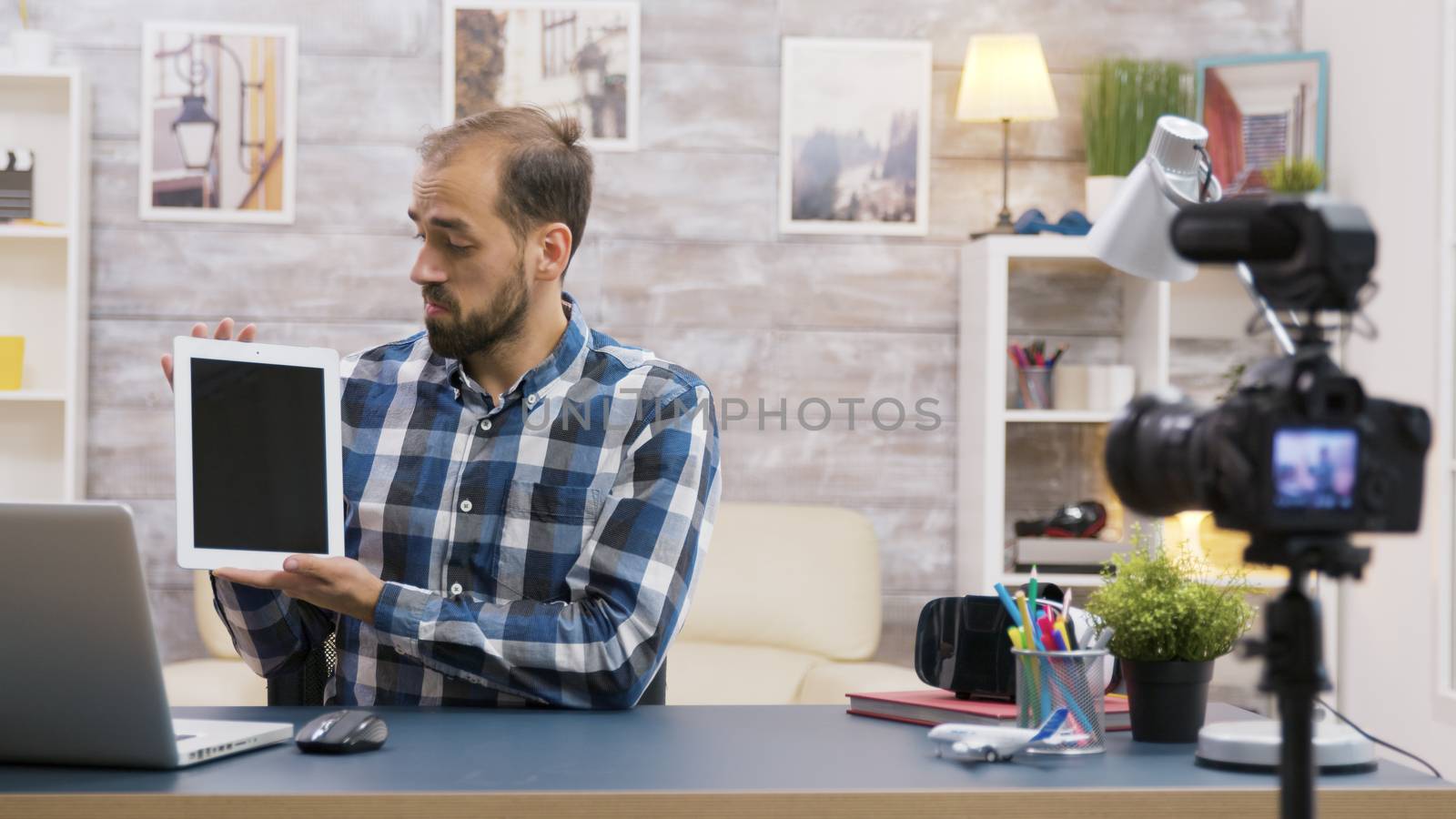 Famous young influencer filming review of tablet. Creative content creator.