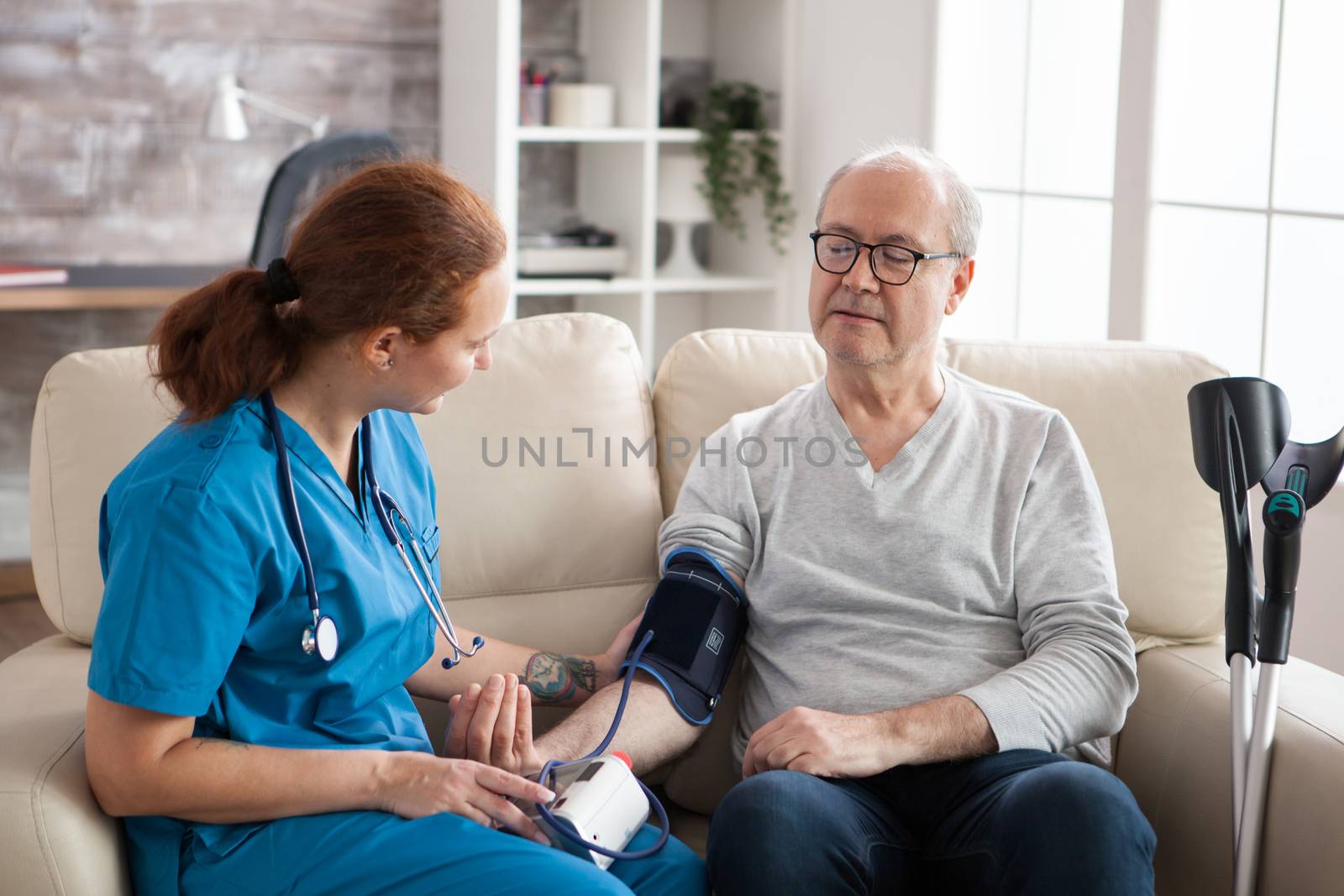 Senior man in nursing home with digital blood pressure device on his arm. Female doctor with old patient.