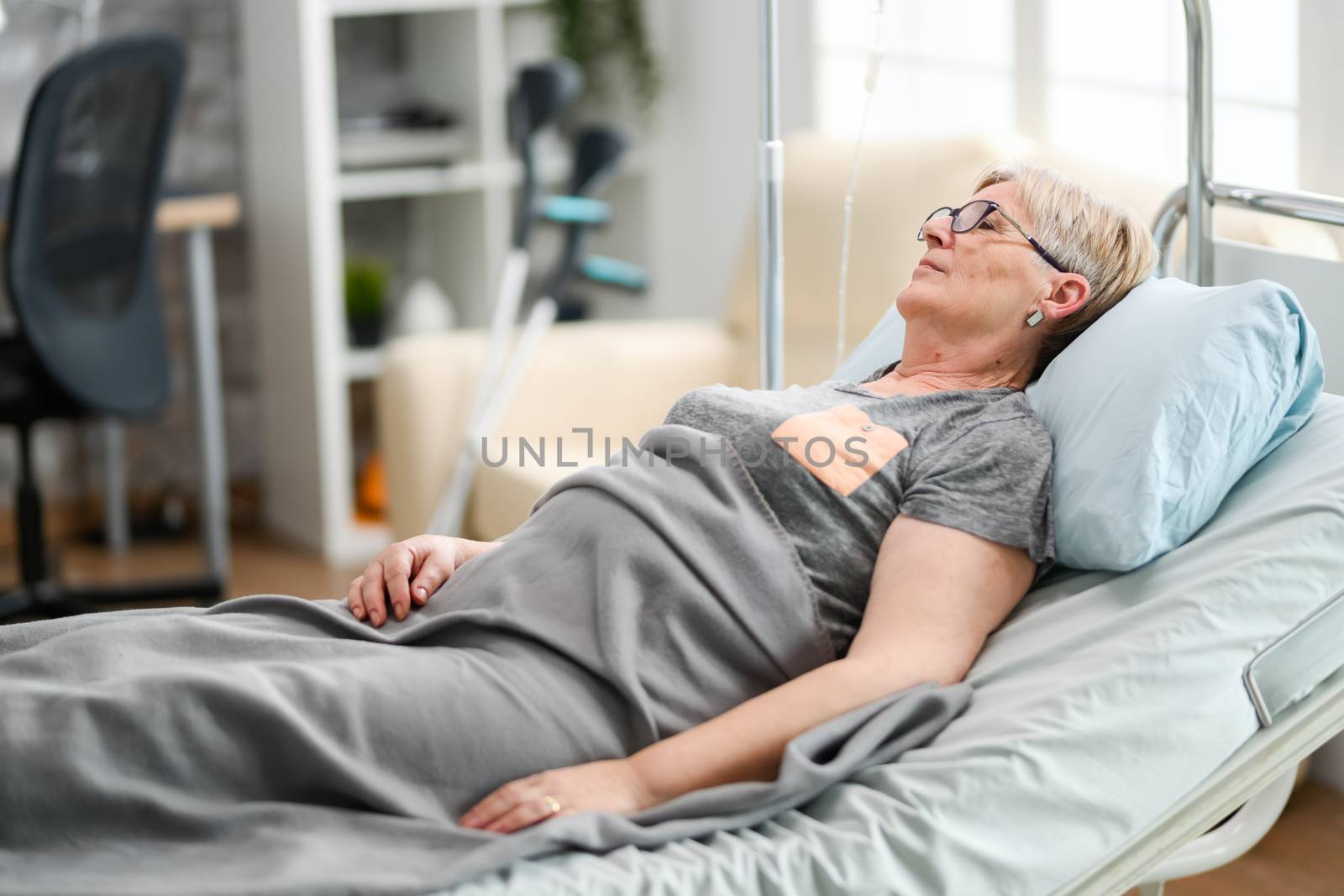 Elderly age woman sleeping in a nursing home bed by DCStudio
