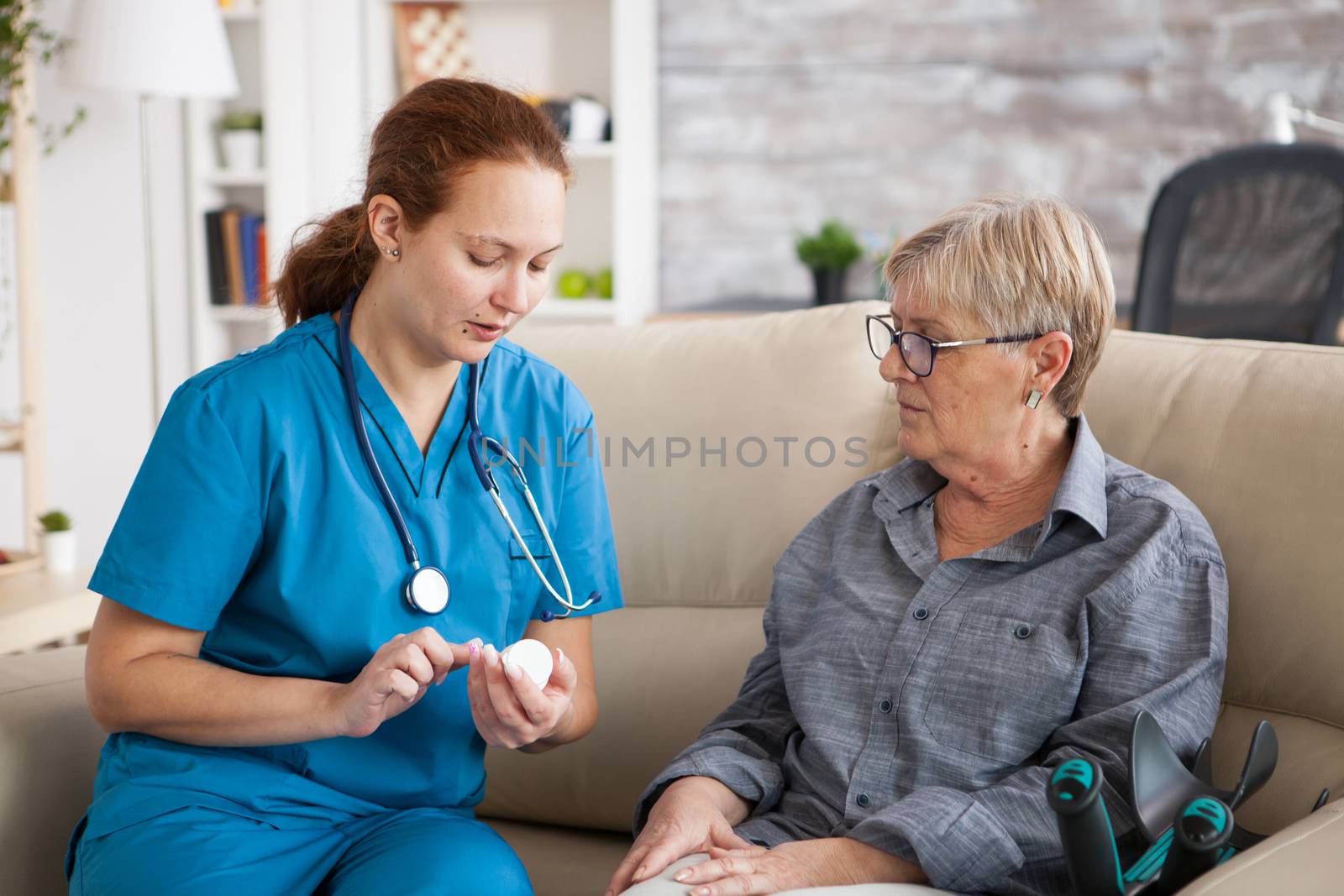 Nurse in nursing home helping senior woman with her pills.