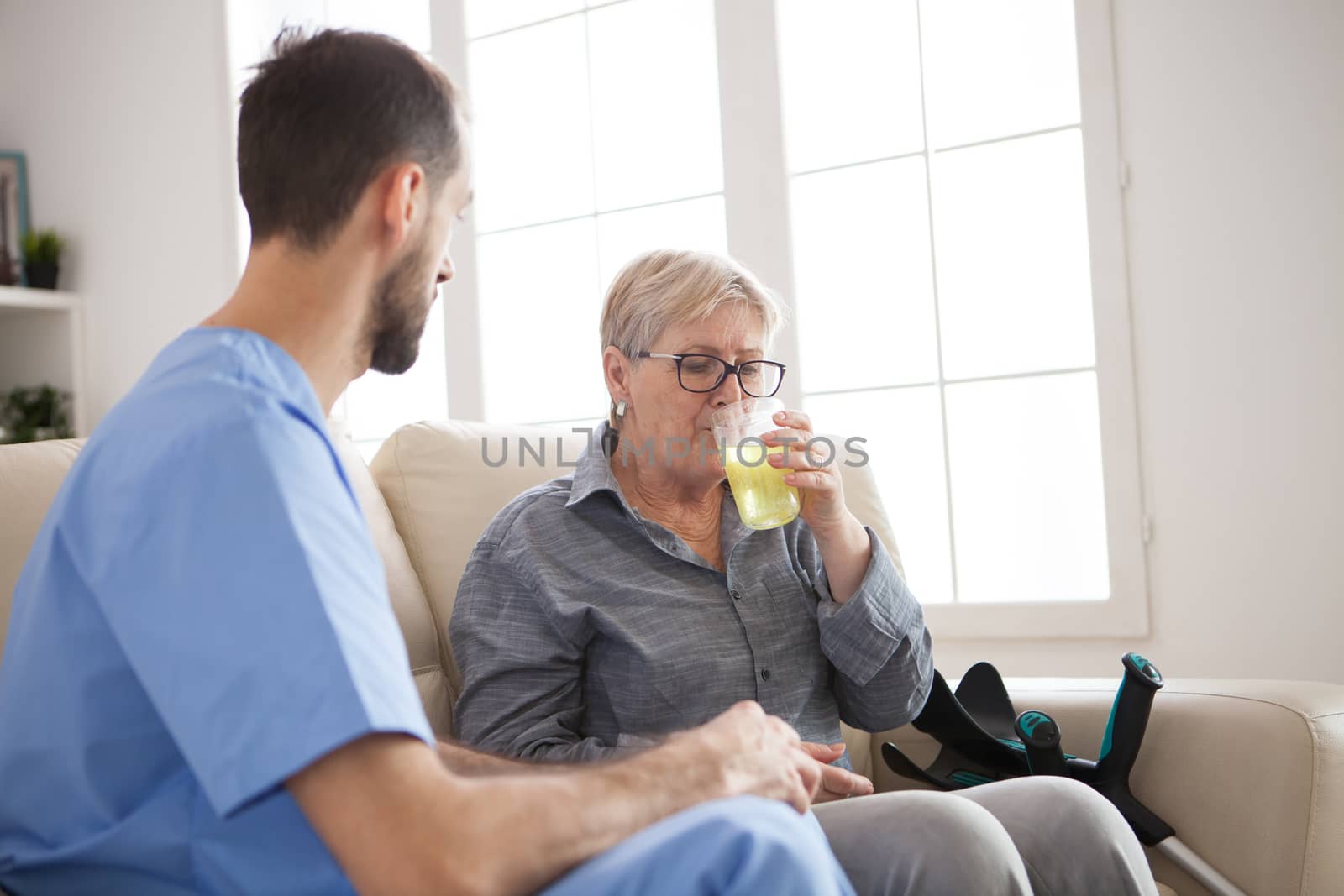 Senior woman in nursing home taking her pills with the doctor next to her.