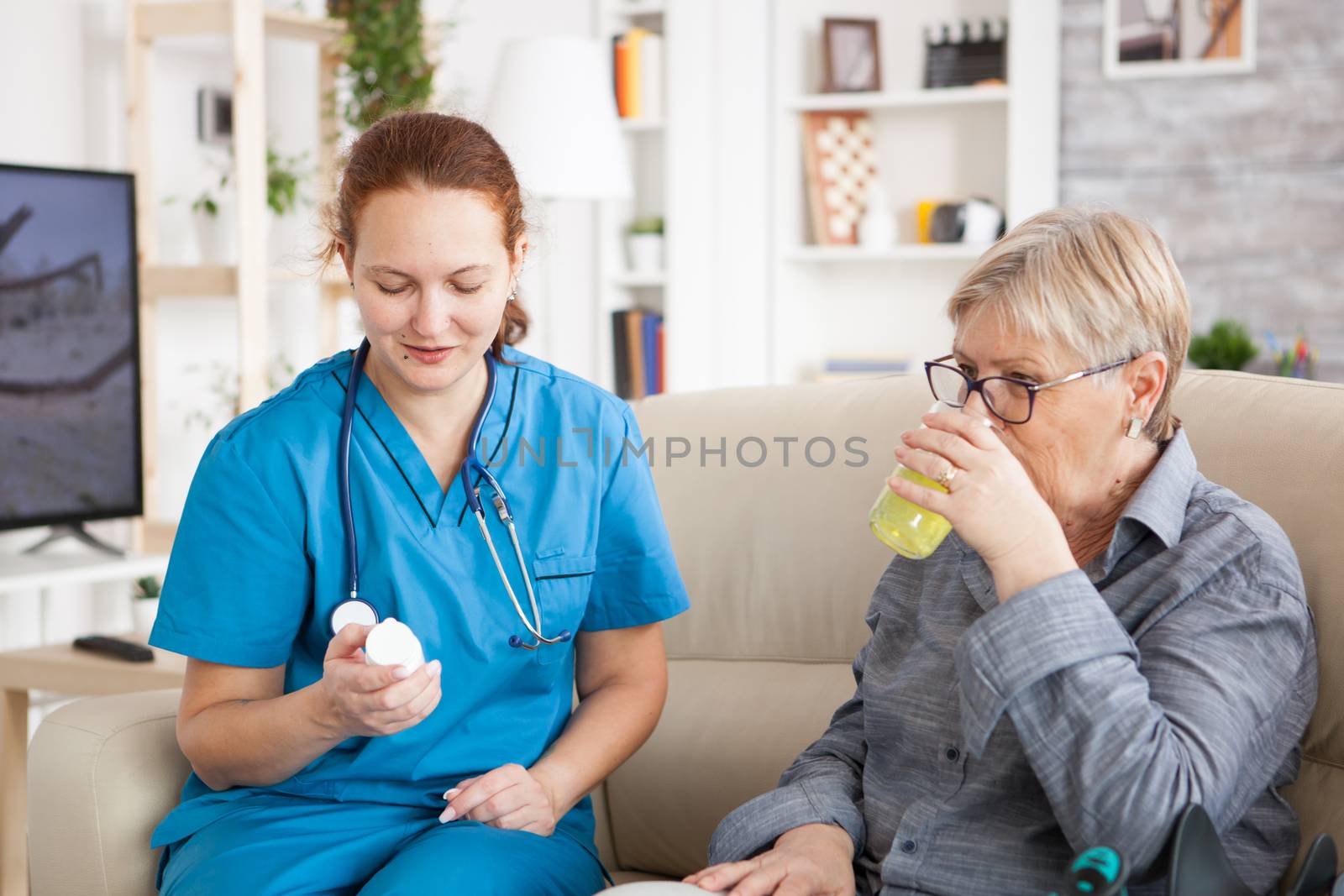 Medical nurse helping senior woman in nursing home to take her pills.