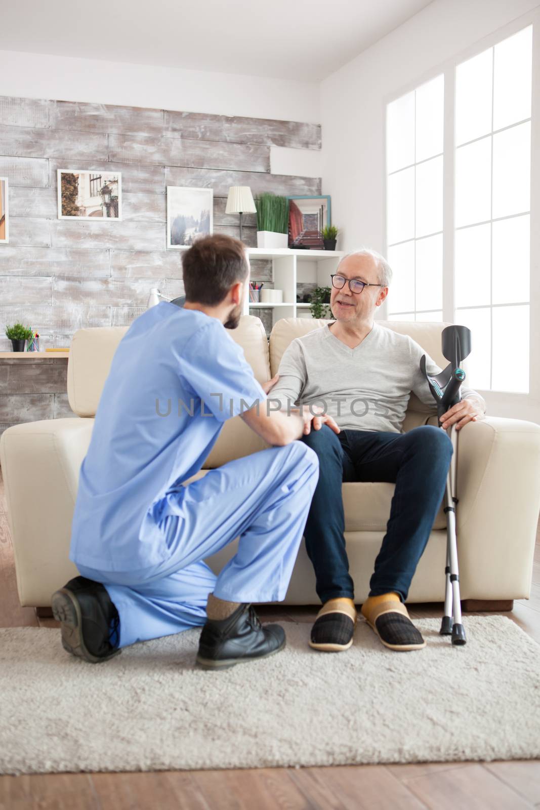 Old man with mental health recognise his doctor in nursing home. Caretaker talking with old man.