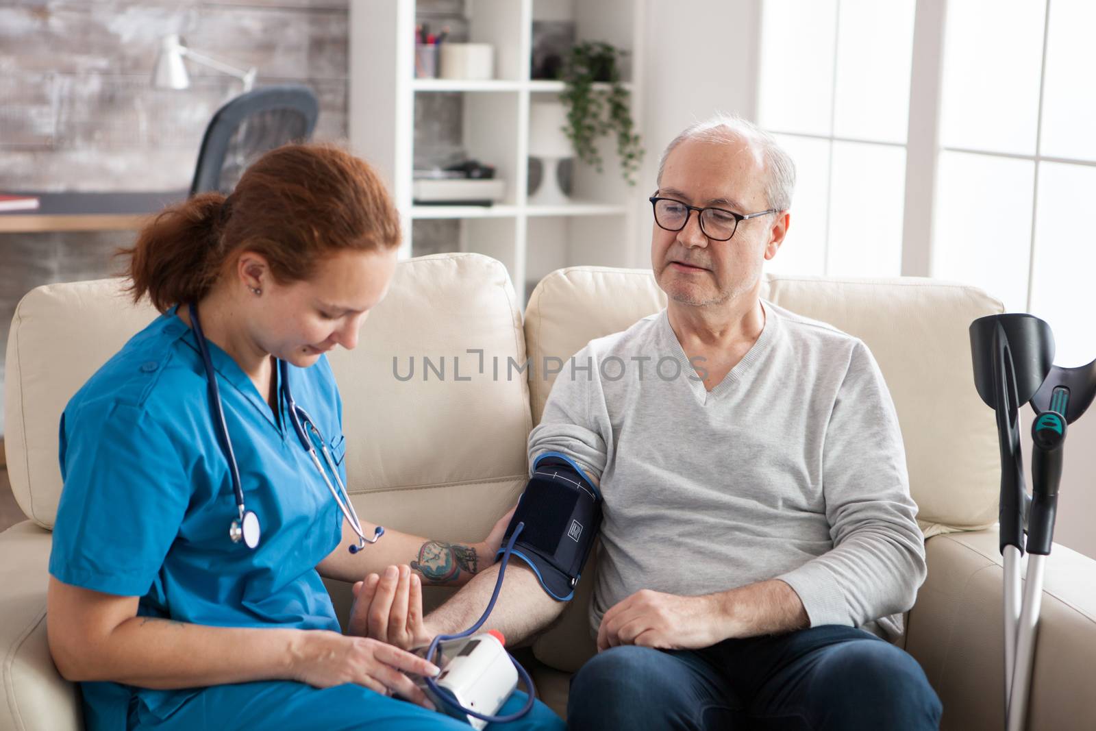 Female doctor reading blood pressure of old man by DCStudio