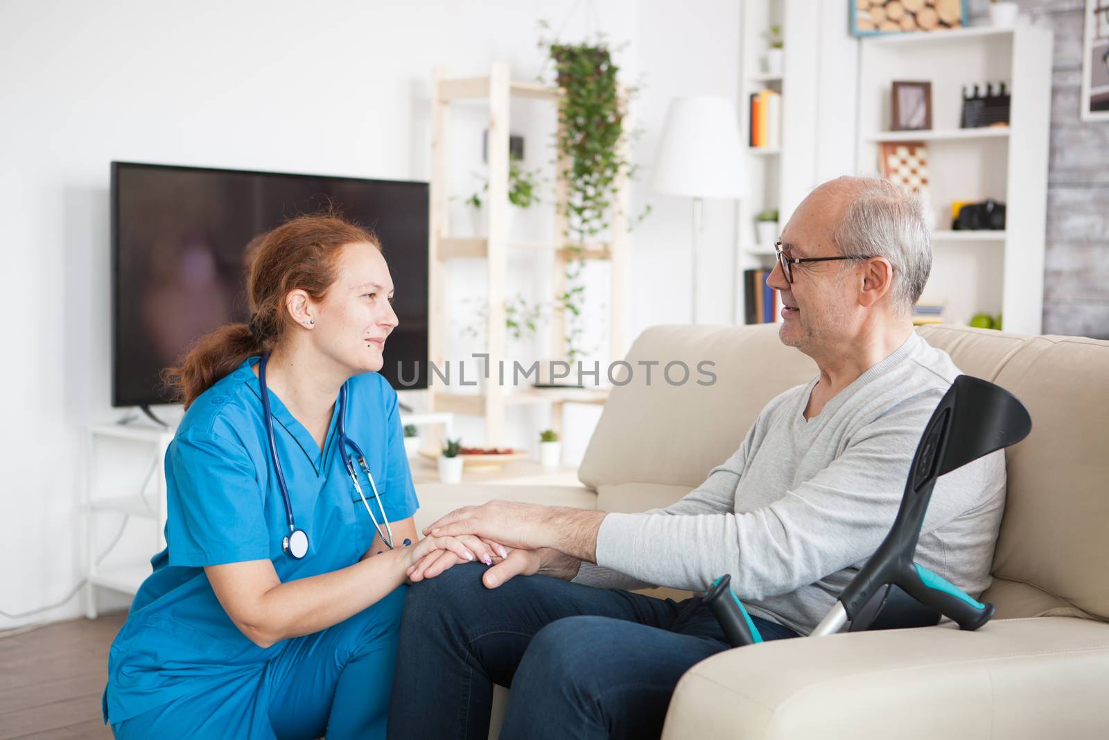 Female nurse smiling and talking with elderly age man by DCStudio