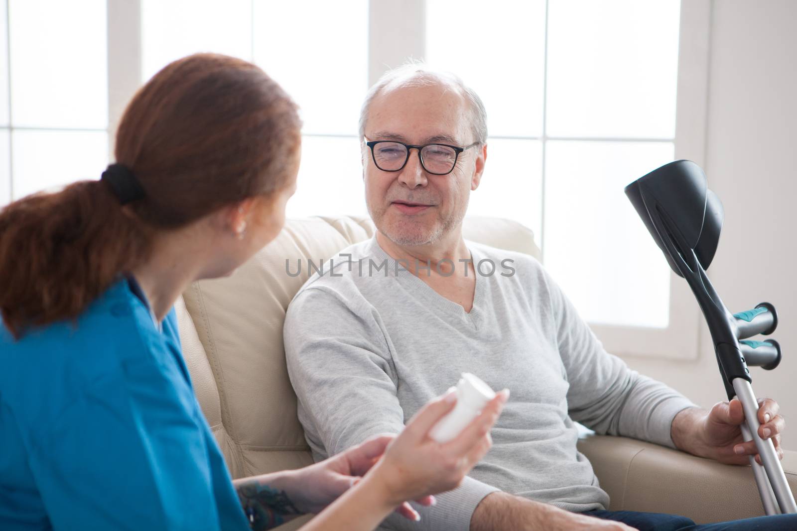 Smiling senior man with crutches in nursing home by DCStudio