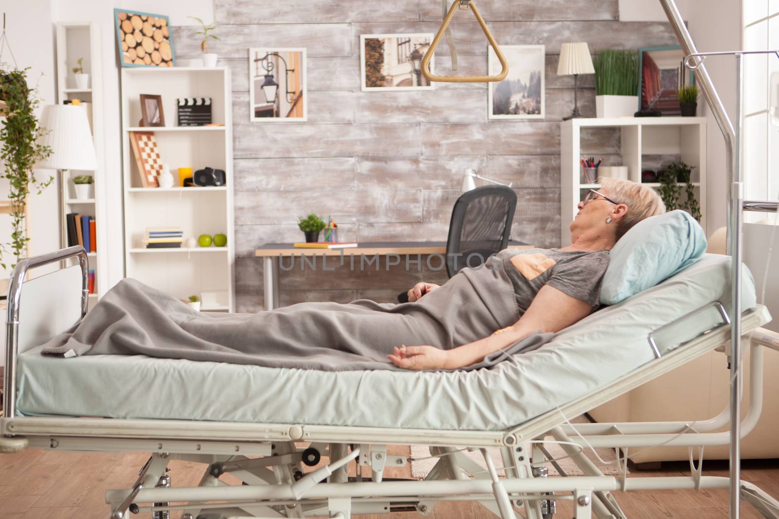 Picture old woman resting in bed in a nursing room by DCStudio