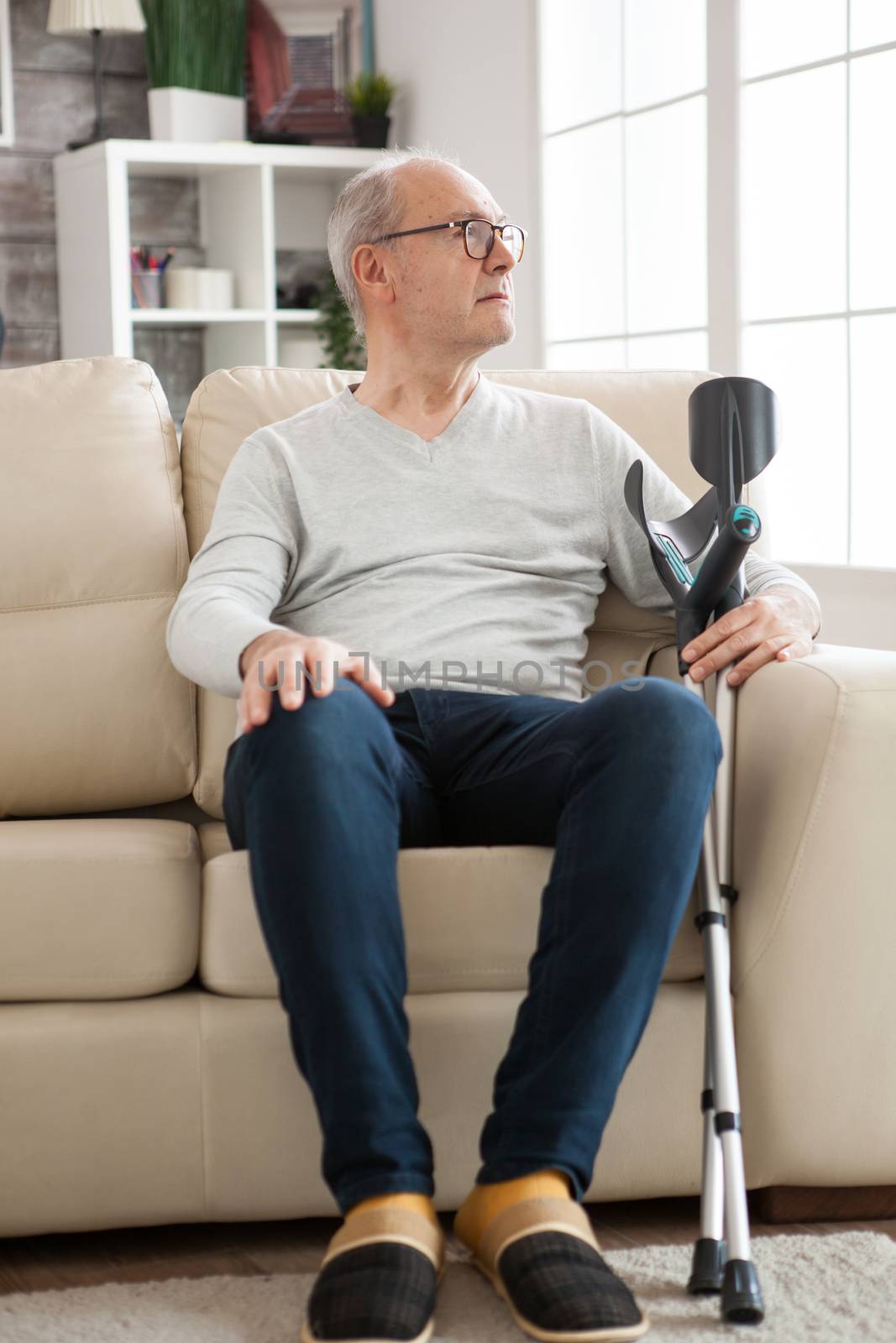 Loney old man sitting on couch in a nursing home by DCStudio