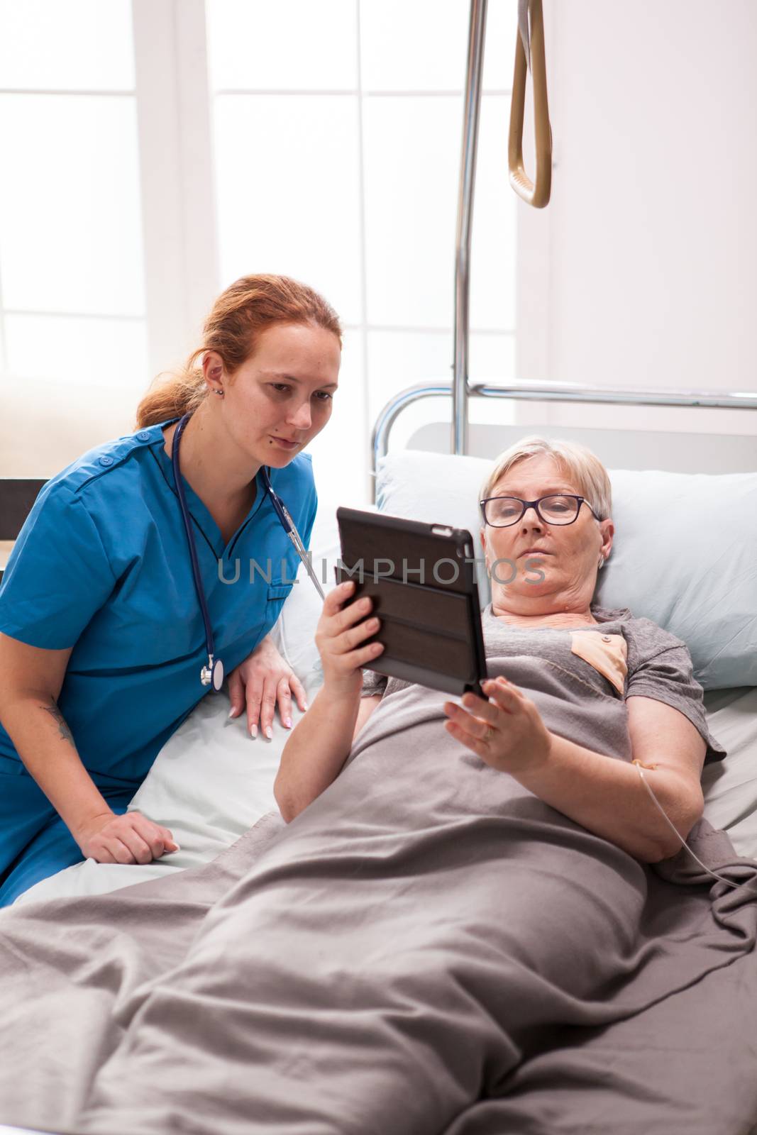 Elderly age woman and female doctor reading on tablet computer by DCStudio