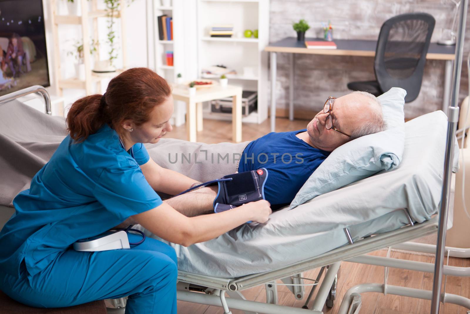 Female nurse doing a blood pressure check up on old man by DCStudio