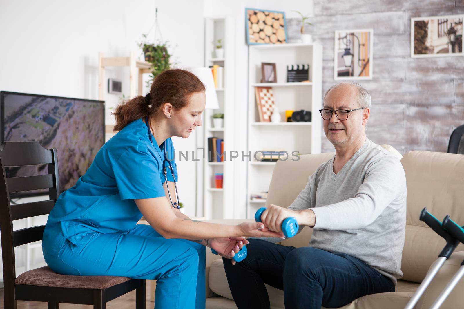 Female nurse doing physiotherapy with senior man by DCStudio