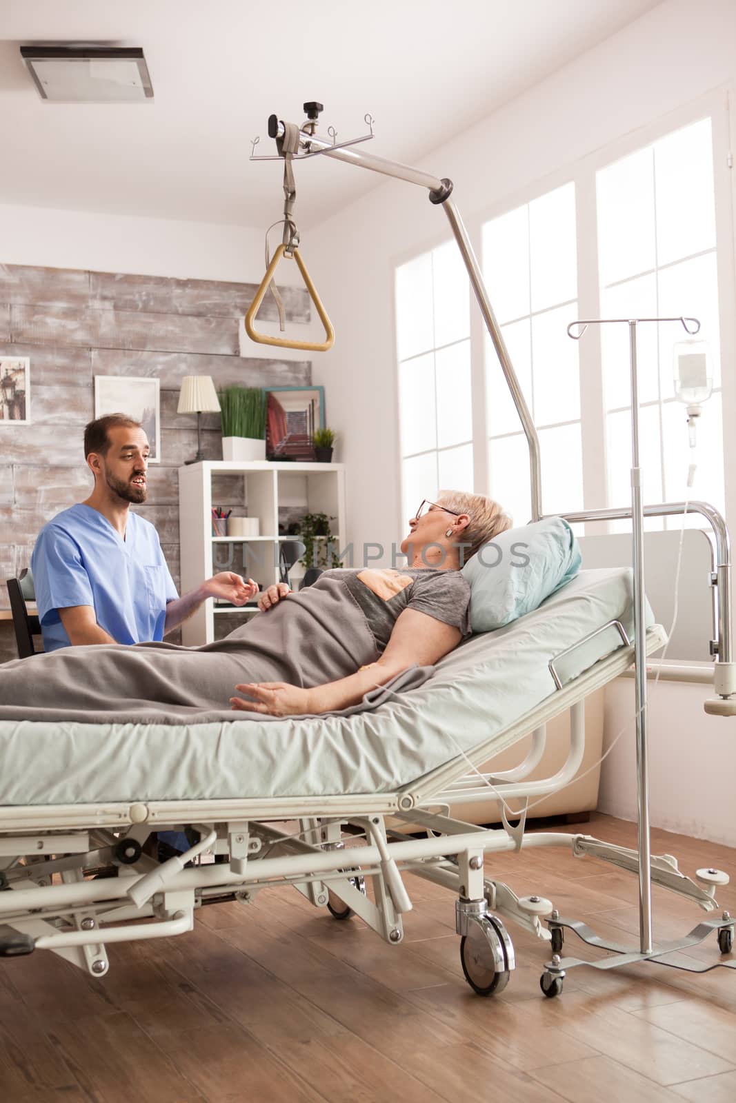 Friendly male nurse talking with senior woman in nursing home.