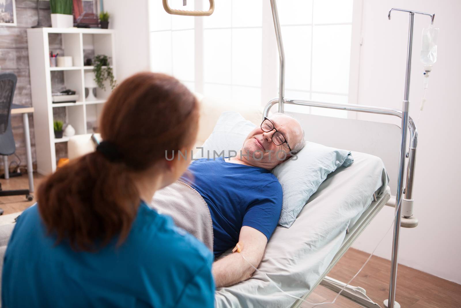 Old man in nursing home smiling to female doctor in nursing home.