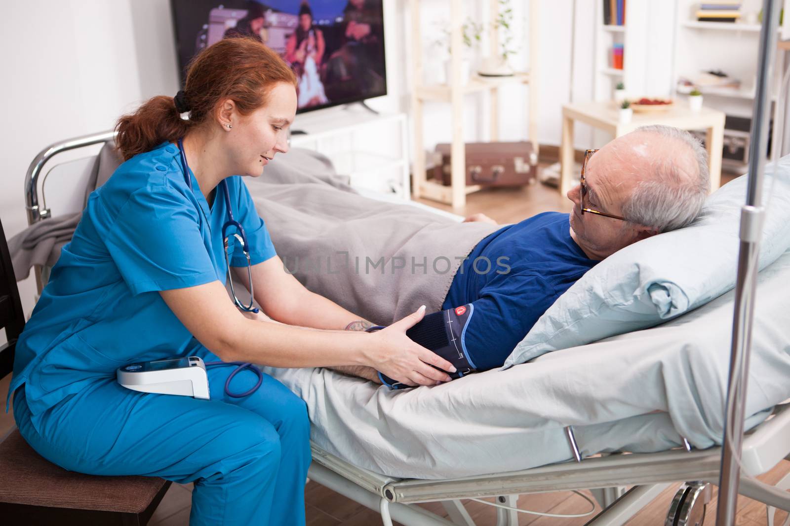 Female nurse checking the blood pressure of retired man by DCStudio