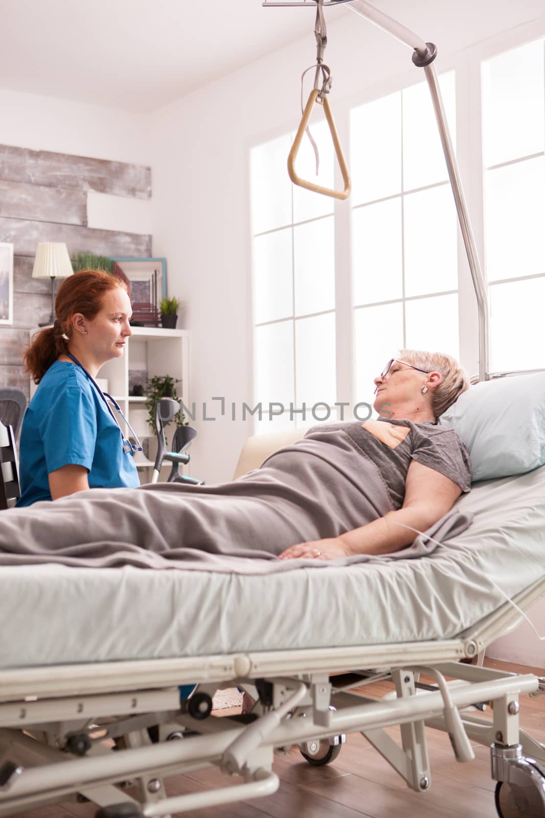 Female doctor in nursing home talking with senior woman with cancer.