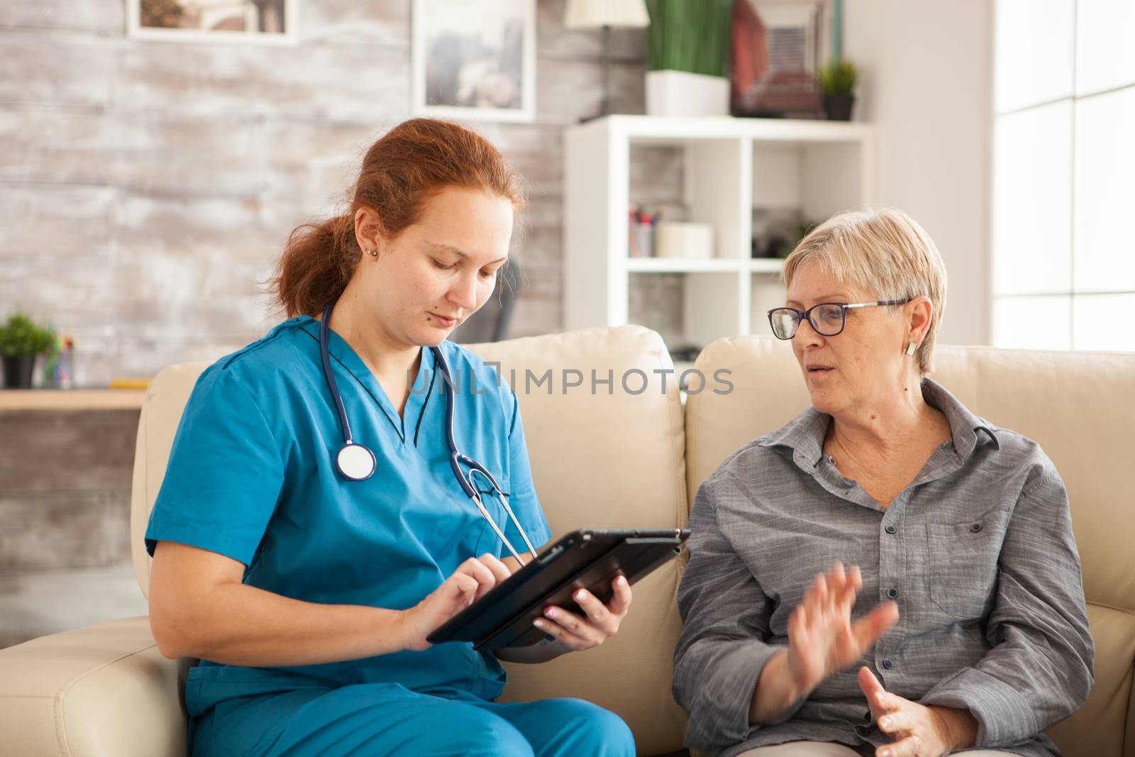 Female doctor using tablet computer and senior woman in nursing home.