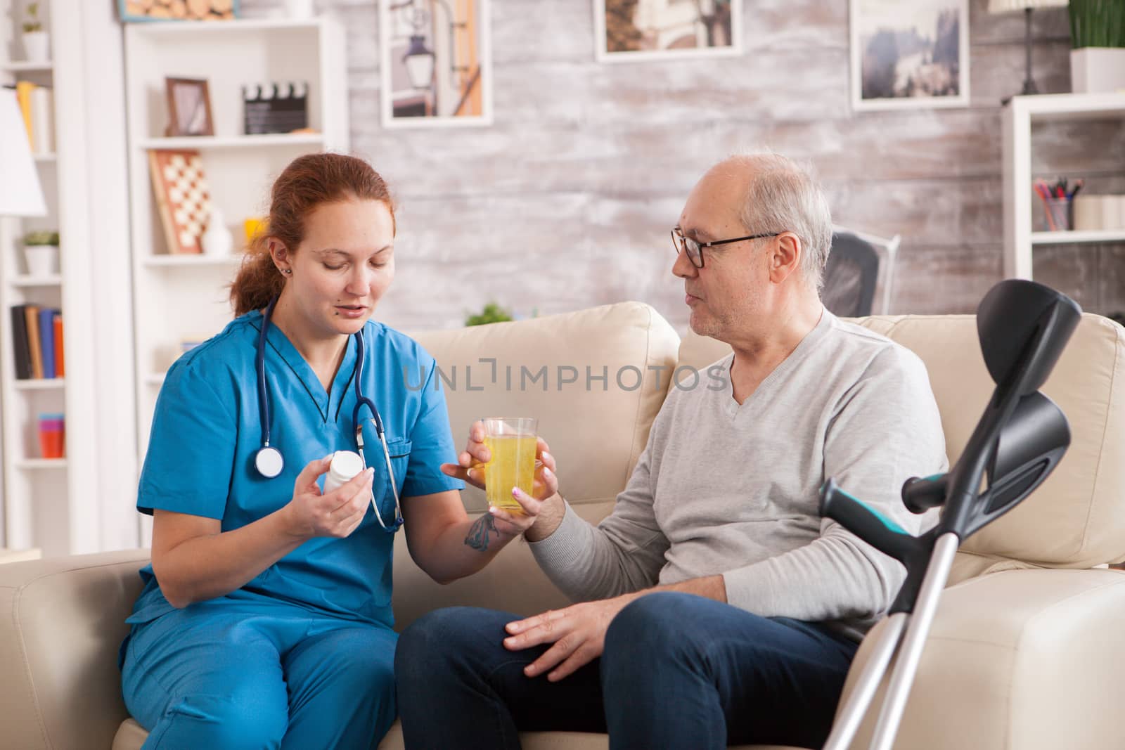 Old man in nursing home helped by female doctor to take his medicine.