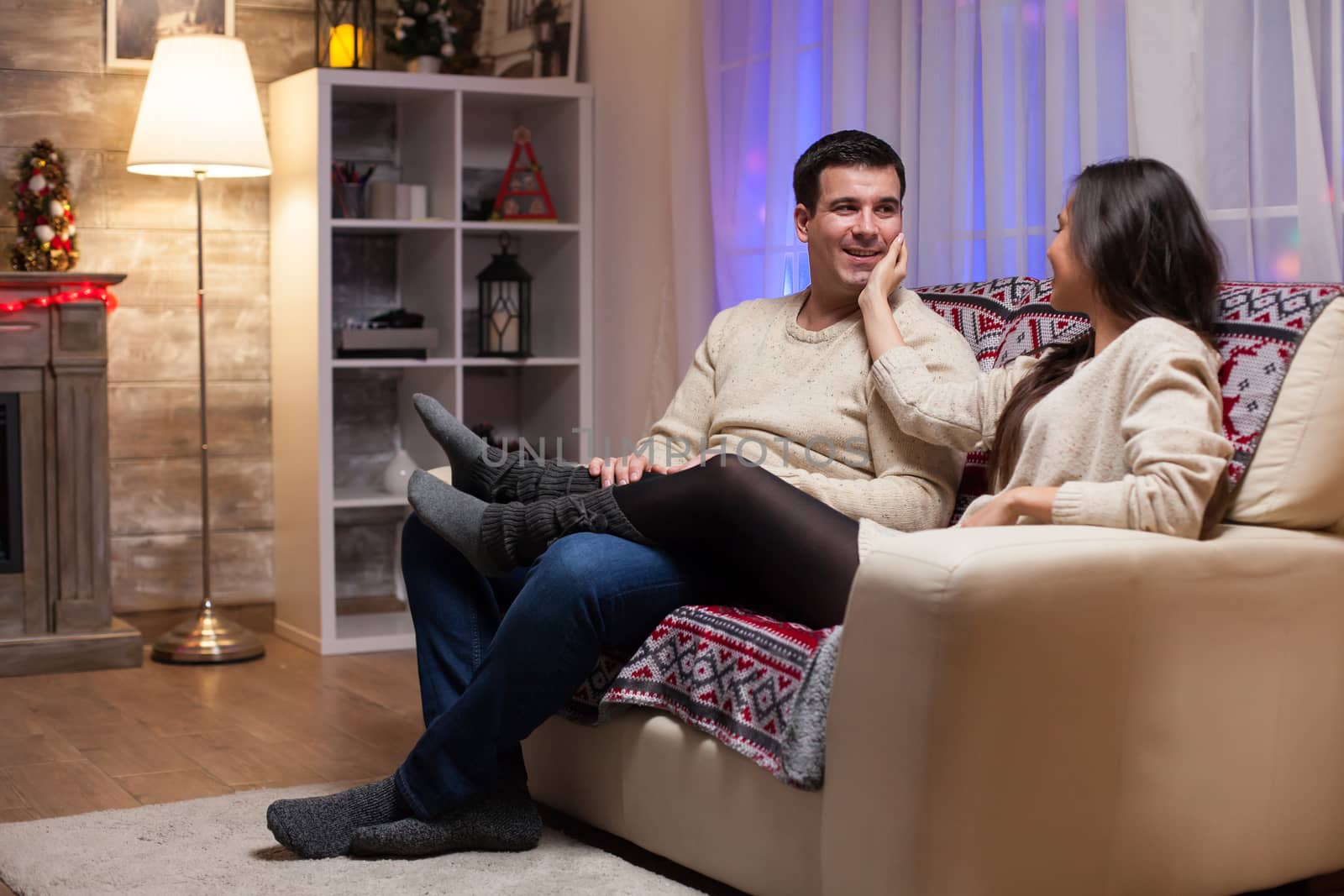 Beautiful young couple sitting on couch celebrating christmas by DCStudio