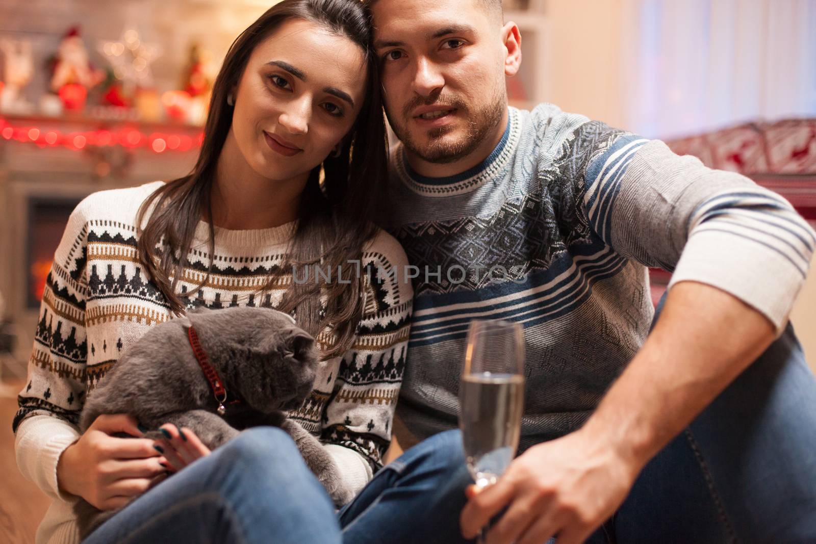 Loving couple with their cat on christmas day looking at the camera.