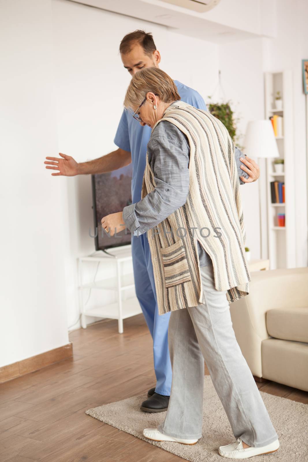 Senior old woman in nursing home helped by male doctor to walk.